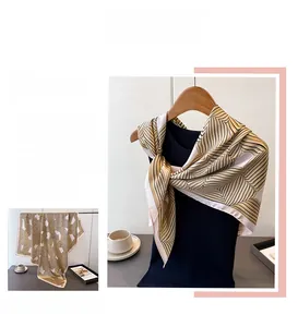 Detail eines Seidenschals mit braunen geometrischen Linien auf einem schwarzen Outfit