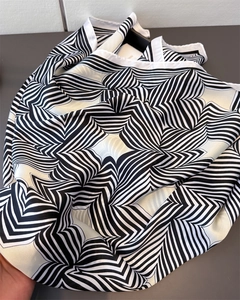 Makro-Detail des Seidensatin-Schals mit schwarz-weißem geometrischem Sonnenstrahl-Muster