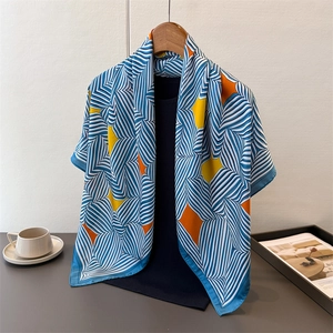 Detailaufnahme eines Seidenschals mit blauen Streifen und gelben geometrischen Mustern