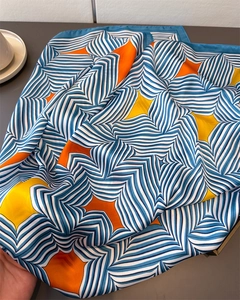 Detail eines Satin-Seidenschals mit blauen Wellenmustern, orangefarbenen Sternen