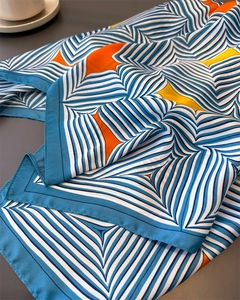 Detail eines seidigen quadratischen Satinschals mit blauen Streifen und Sternmustern