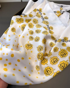 Close-up of satin scarf with yellow rose print, polka dots and silk-like glossy texture