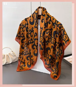 Detailed view of satin square scarf with vintage golden scroll patterns and red edges