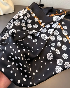 Close-up of floral satin silk scarf with camellia print and golden chain patterns