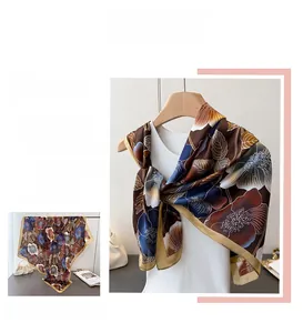 Detail of silk-like square scarf with elegant floral patterns and golden border