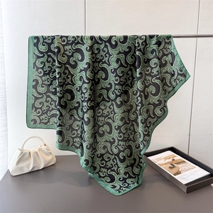 Elegant emerald green paisley satin square scarf displayed on a metallic stand