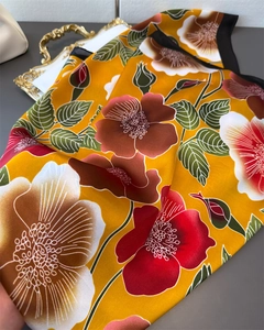 Close-up of bright yellow silk scarf featuring elegant floral patterns and a satin finish