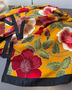Macro detail of floral silk scarf featuring yellow base with red and white flower patterns