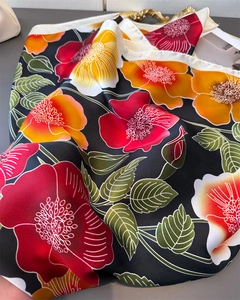 Close-up of silk-feel scarf featuring high-contrast floral print and rolled edges