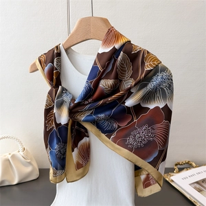 Close-up of floral silk scarf with champagne gold edges on a wooden hanger