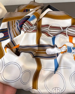 Detailed close-up of equestrian silk scarf with horse bit patterns and satin texture