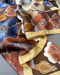 Close-up of vintage floral silk scarf with gold satin edges and elegant brown pattern