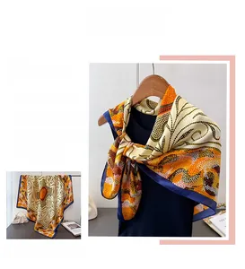 Détail d'un foulard en soie avec motifs géométriques orange et bordure bleu marine