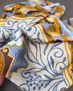 Détail du foulard en soie affichant des motifs géométriques et une finition de bordure