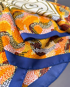 Gros plan d'un foulard carré en soie synthétique avec motifs à pois et bordures bleues
