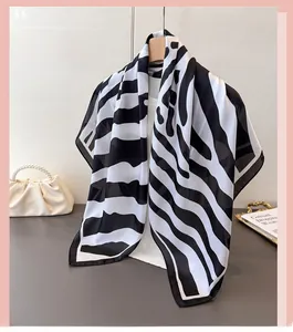 Detail of silk-feel scarf with wavy black and white prints hanging on a hanger