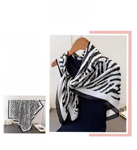 Detailed view of elegant zebra print silk scarf with satin finish and black stitched edges