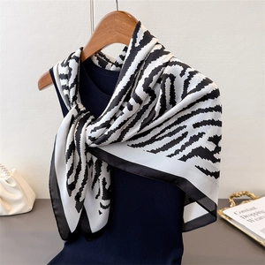 Elegant zebra print faux silk scarf displayed on a wooden hanger over a navy sweater