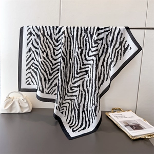 Elegant black and white zebra print silk square scarf displayed with luxury accessories