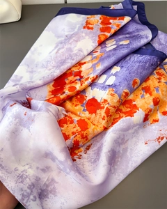 Dettaglio del foulard in seta con motivi artistici arancioni e viola e bordo blu