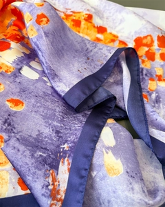 Dettaglio di sciarpa in seta con stampe artistiche viola e arancioni e bordino in raso blu