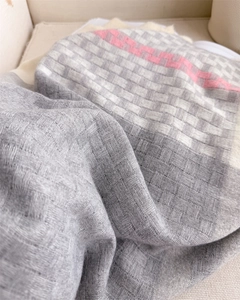 Detailed basketweave texture of a soft plaid winter scarf with pink stripes and tassels