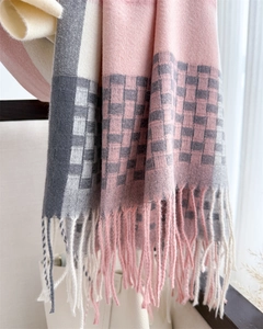 Detailed close-up of pink and grey plaid scarf texture with soft fringe edges