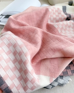 Macro detail of soft plaid scarf texture with pink and grey weave and fringe edges