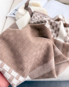 Detailed texture of brown and beige plaid knit scarf featuring thick waffle weave fabric