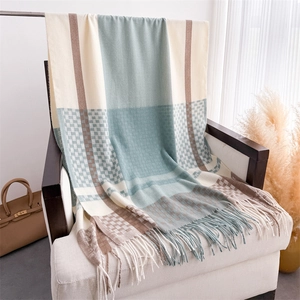Detail of plaid scarf with tassels draped on a chair showing the soft cashmere-like texture