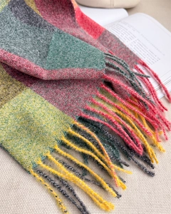 Gros plan d'une écharpe d'hiver à carreaux colorés avec franges sur un tissu rustique