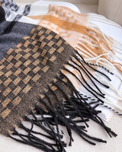 Close-up of soft plaid knit scarf featuring dense tassel edges and woven texture