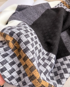 Macro detail of plaid cashmere scarf showing woven texture and fringe in multiple colors