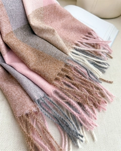 Gros plan d'une écharpe à carreaux rose et gris avec franges et texture cachemire