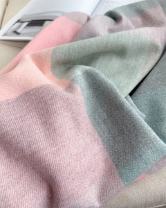 Gros plan d'une écharpe à carreaux pastel montrant le tissage sergé et les franges