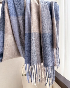 Détail de la texture d'une écharpe à carreaux épaisse avec franges bleues et beige