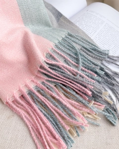 Détail de l'écharpe à carreaux rose et gris montrant la texture douce et les franges