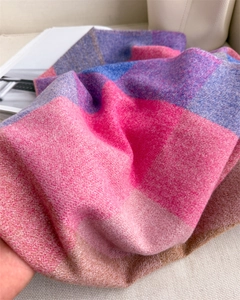 Gros plan d'une écharpe à carreaux douce montrant la texture tricotée rose et bleue