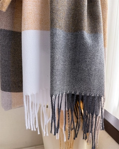 Détail d'une écharpe à carreaux douce avec franges en blanc, gris et texture caramel
