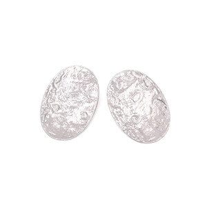 Close-up of silver oval drop earrings with unique hammered metal texture and vintage finish