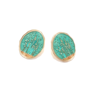 Detail of oval forest earrings with emerald green enamel landscape and gold tree patterns