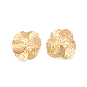 Macro shot of gold floral earrings featuring artistic hammered metal texture and petals