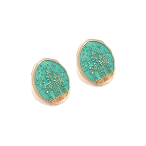 Detail of oval gold earrings with mint green forest landscape and tree relief