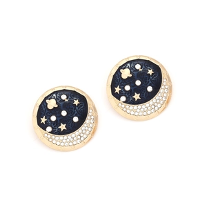 Close-up of gold moon and star stud earrings with blue enamel and crystal details