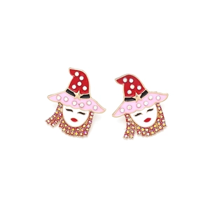 Close-up of enamel cartoon girl earrings with red witch hats and pink rhinestones