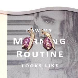 Macro detail of snail studs with purple enamel, gold plating and crystal inlay