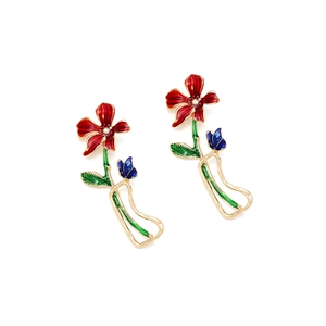 Détails de boucles d'oreilles fleurs et papillon avec pétales rouges et émail bleu