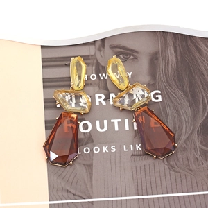 Retro geometric resin earrings with yellow and amber gemstones on magazine background