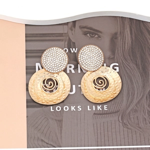 Retro gold spiral earrings with rhinestones and hammered texture on a stylish magazine