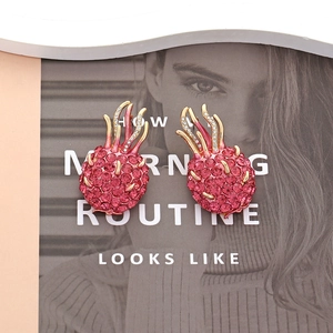 Sparkling pink rhinestone dragon fruit stud earrings with gold leaves on magazine